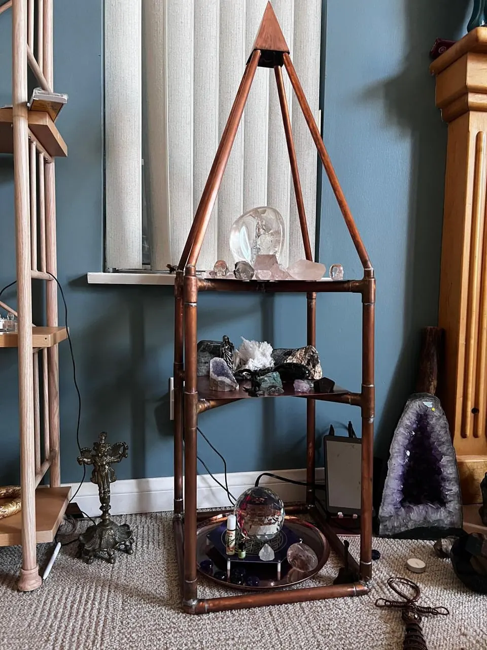 Golden Rectangle Nubian Pyramid Altar indoors, its copper shelves holding crystals and small objects